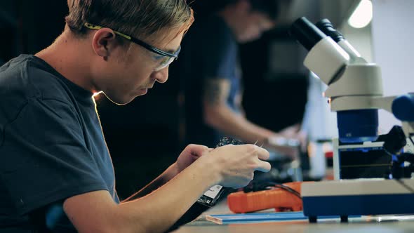 Service Specialist Digging in Mobile Device Components with Tweezers