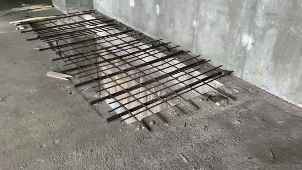 A Large Rectangular Hole in the Concrete Floor is Blocked By an Iron Grating at a Construction Site