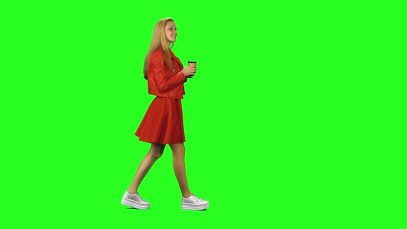 Blonde Girl Calmly Walking and Drinking Coffee on Green Screen Background. Chroma Key, Shot. Profile