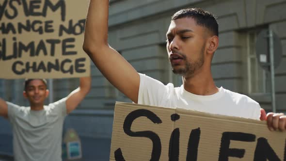 Two mixed race men on a protest march holding placards raising hands and shouting