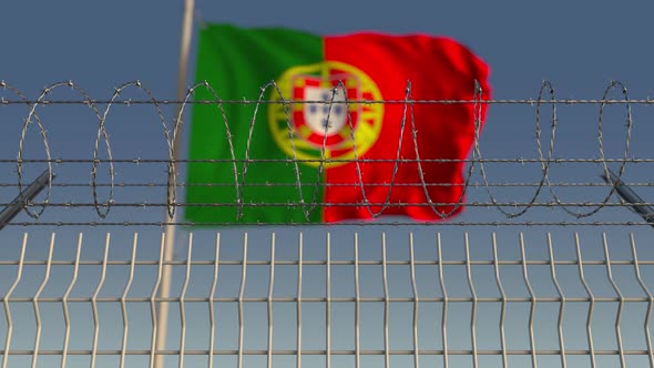 Waving Flag of Portugal Behind Barbed Wire Fence