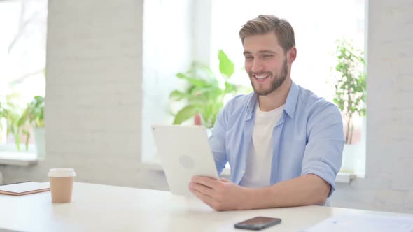 Creative Man Making Video Call on Tablet in Modern Office