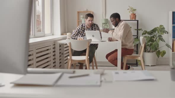 Male Colleagues Discussing Work in Office