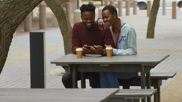 Couple using mobile phone in outdoor cafe 4k
