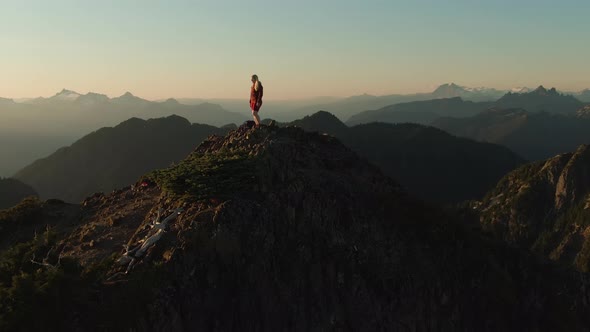 Adventurous Caucasian Woman Hiking on Top of a Rocky Mountain Cliff