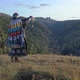 An Old Shaman Performs a Magic Ritual with the Help of a Bell Standing on the Top of a Mountain - VideoHive Item for Sale