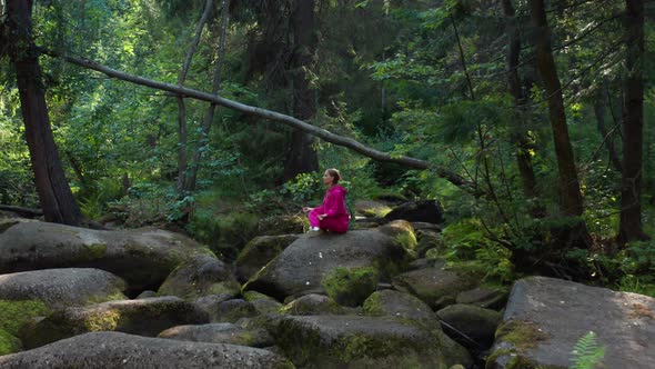 A Girl Sits on a Rock and Meditates in the Forest