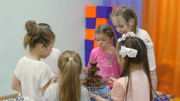 Children's Playroom. Children Eat Chocolate From a Chocolate Fountain