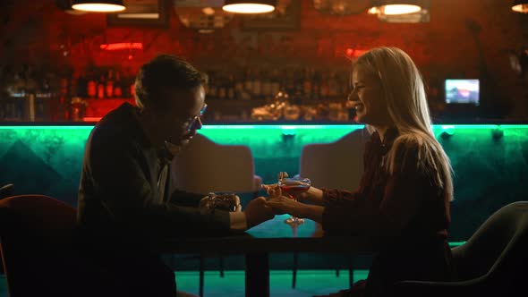 A Spectacular Couple Having a Date in the Bar - a Man Holding Woman's Hand and Talking To Her