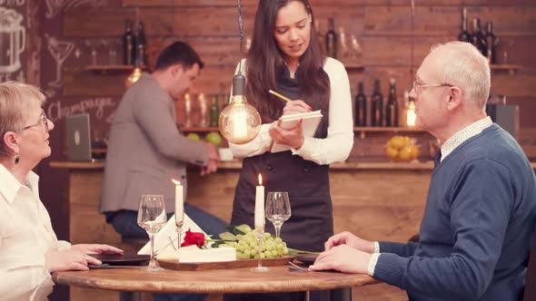 Young Pretty Waitress Taking the Order From an Old Couple