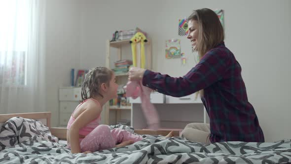 Mom Puts Her Daughter in a Sweater on the Bed