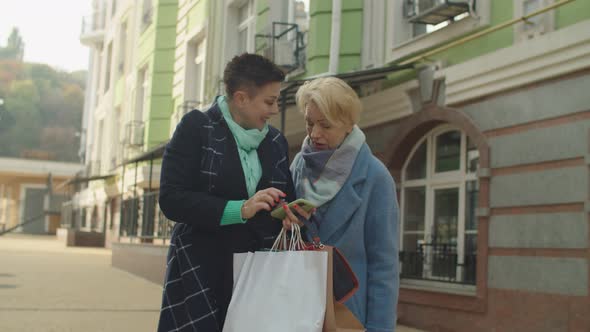 Mature Women Browsing Phone Using Mobile App Via Internet Outdoors