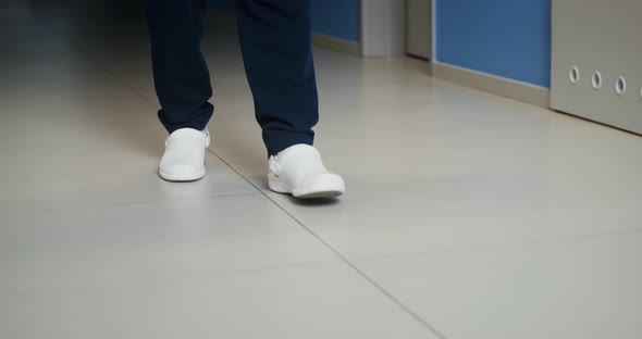 A Man in White Rubber Shoes Walks Along the Corridor of the Hospital