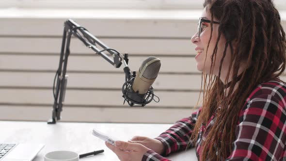 Concept of Streaming and Broadcasting. Young Cheerful Girl in the Studio Speaks Into a Microphone