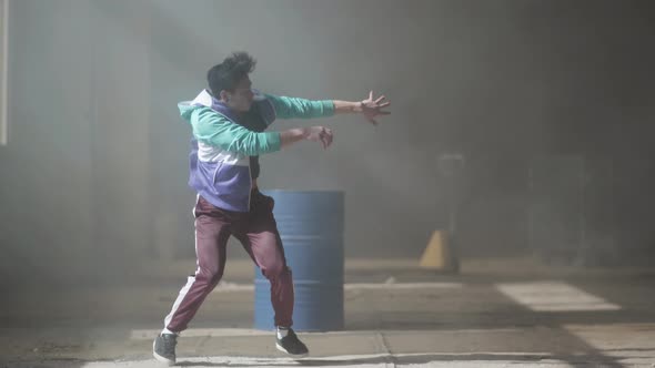 Skillful Young Hip-hop Dancer Dancing Near the Barrel in an Abandoned Building in the Fog