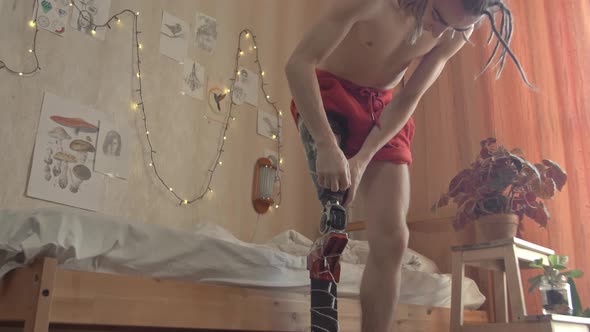 Guy Fastens Bioprosthesis with Fairy Lights on Leg in Room