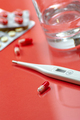 Antibiotics, a glass of water and a thermometer on a red background. Photo shallow depth of field. - PhotoDune Item for Sale