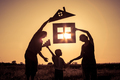 Happy family standing on the field at the sunset time. They build a house. - PhotoDune Item for Sale