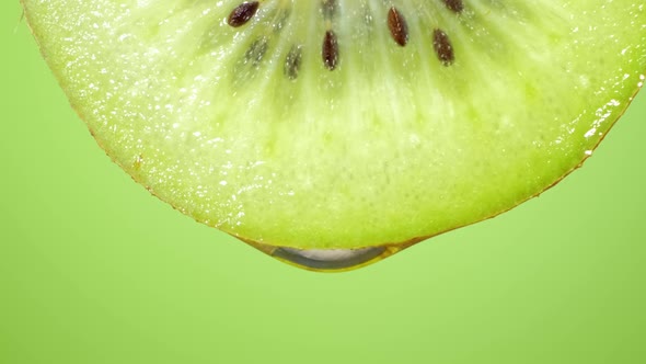 Close Up or Macro of a Slice of Kiwi, a Drop of Water Falls in Slow Motion.