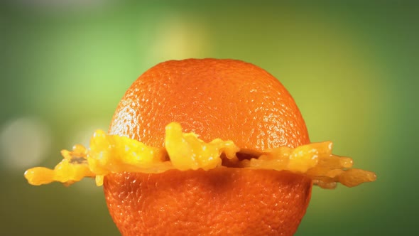 Fresh Orange Fruit Squirting and Burst with Juice in Slow Motion in Green Nature Background