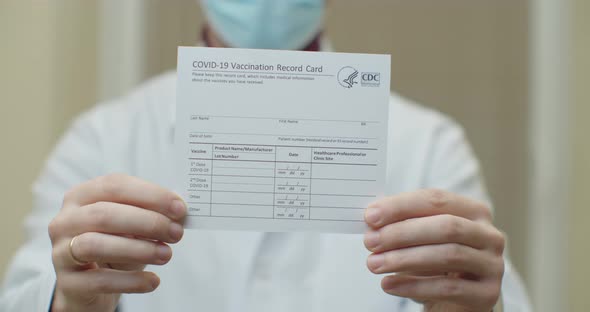 Doctor Is Holding a Vaccination Record Card