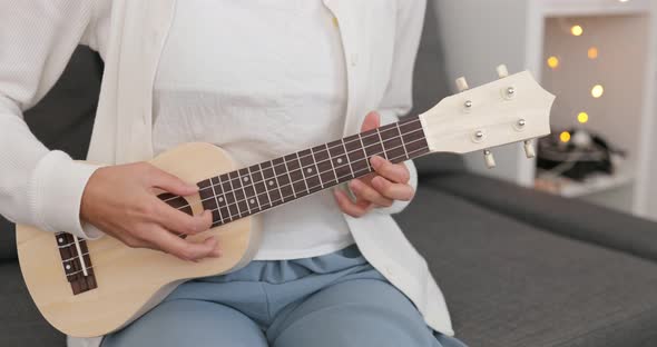 Woman play ukulele at home