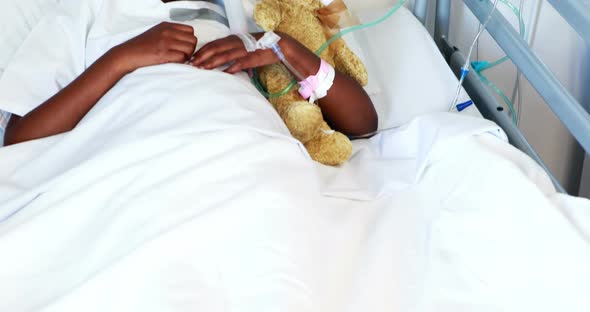 Sick girl in oxygen mask resting with teddy bear
