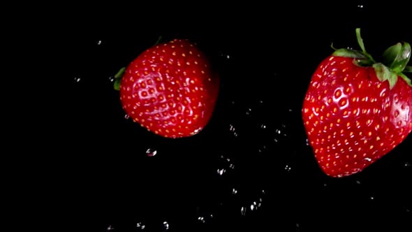 Close-up of Large Strawberries Flying Towards Each Other on the Black Background