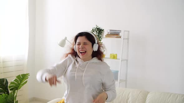 Happy Woman Listening To Music and Dancing in Living Room