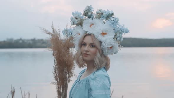 Woman in Ukrainian national costume with a wreath on her head. Embroidery. View of the river. Woman