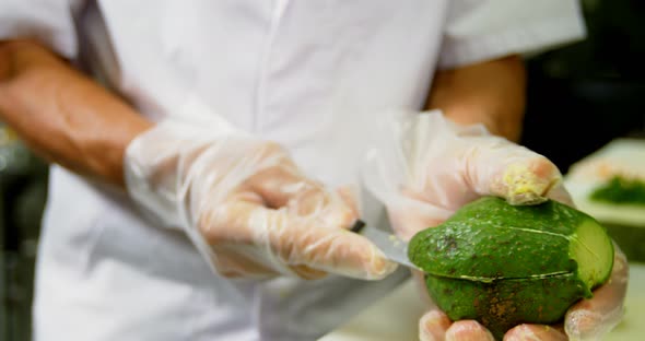 Male chef cutting avocado fruit in kitchen 4k