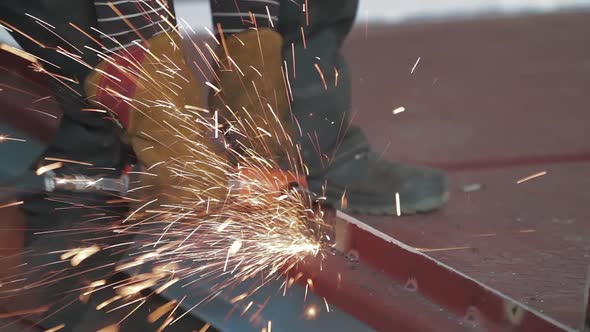 Male Hand Cuts Off Pieces of Metal Blank with Angle Grinder. Cutting of a Steel with Splashes of