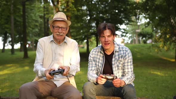 Focused Grandfather Playing Video Game with His Grandson