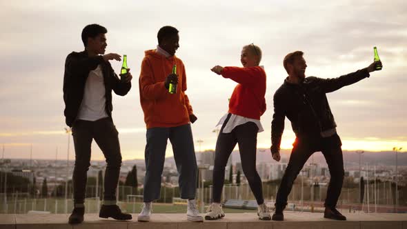 Multiethnic Friends Dancing and Drinking in a Rooftop at Nightfall