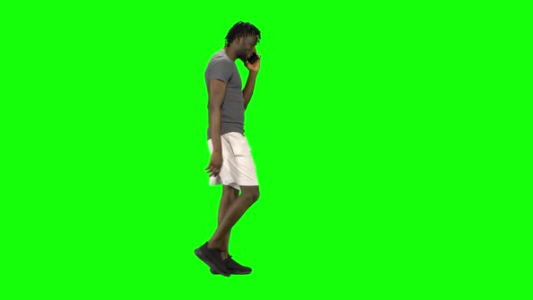 African American Man Walking and Talking on the Mobile Phone at Green Screen, Chroma Key. Profile