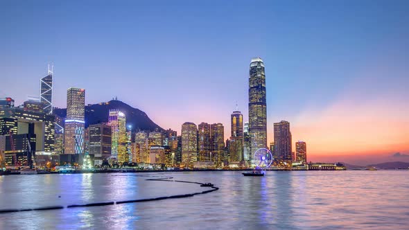 Hong Kong China Skyline Panorama with Skyscrapers Day To Night From Across Victoria Harbor Timelapse