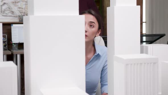 Young Female Architect Looking at 3D Printed Building Models