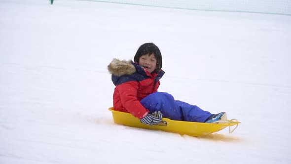 Asian Mother And Her Son Playing Sled Under Snow Fall