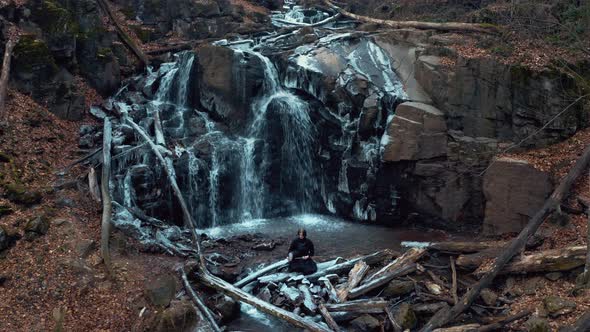 Man Practicing Kendo with Bamboo Sword on Waterfall Background. Aerial