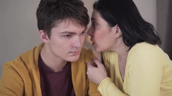Close-up of Brunette Caucasian Woman Whispering on Ear of Teenage Boy. Mother Sharing Secrets with