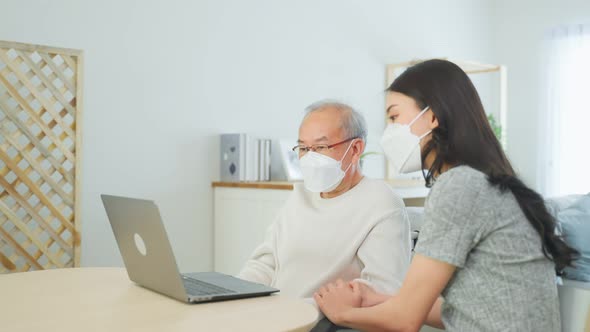 Asian senior male and daughter use computer laptop video call with doctor during pandemic.