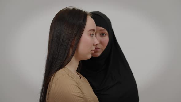 Side View Serious Young Slim Woman with Blurred Twin Sister in Black Hijab at Background