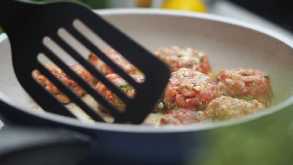 Unrecognizable person cooking meatballs on frying pan with oil