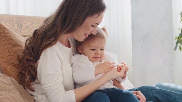 Caucasian Young Mother with Baby Little Girl Talking Hugs Spends Time Together at Home Loving Mom