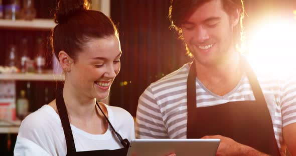 Waiter and waitress discussing over digital tablet