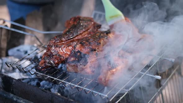 Delicious Beef or Pork Ribs Frying on a Charcoal Grill Being Covered with Red Gravy Sauce Brush