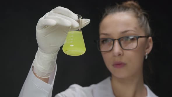 Female Scientist Checking in Test Flask Chemical Liquid with Dark Precipitate