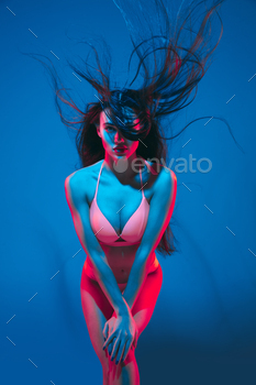 Attractive brunette model on blue studio background in neon light / Photodune, Misc