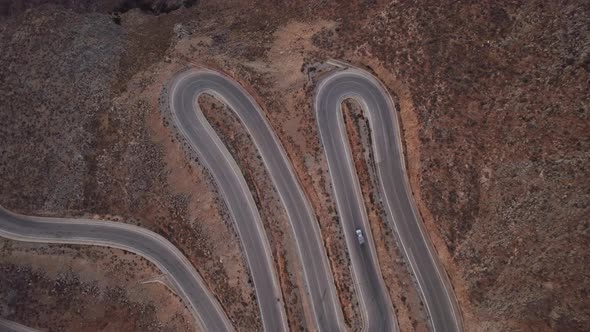 Small cargo truck going on the U-turn in the mountains. Aerial top down view of the zig-zag turn.