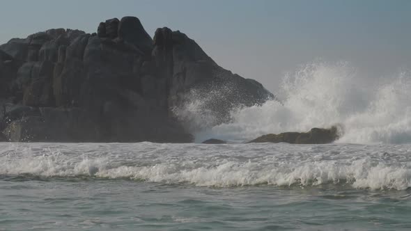 Heavy Ocean Wave Beats on Grey Rocks Near Tropical Coast